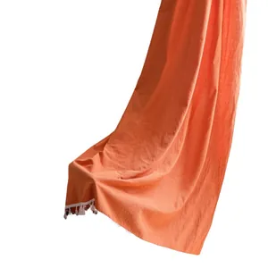 Tenda arancione in cotone e lino con frange di nappe bianche appesa verticalmente