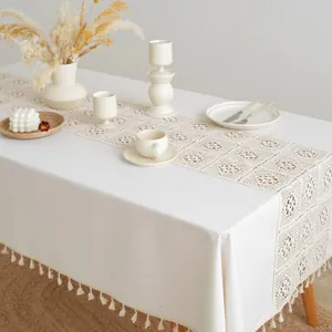 Close-up of cream linen tablecloth featuring hollow crochet patterns and tassel edge detail