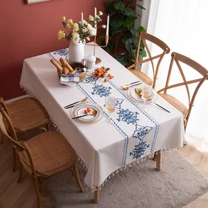 Detail of floral linen tablecloth featuring vintage blue patterns and beige tassel fringe