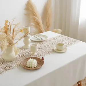 Detail of bohemian hollow crochet table runner with tassels on a white cotton cloth