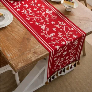 Close-up of red Christmas table runner with bird floral pattern and dark tassels