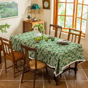 Close-up of green jacquard tablecloth with daisy pattern and white tassel fringe edge