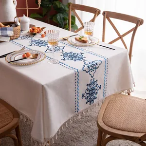 Detailed close-up of blue geometric floral embroidery and fringe on cotton linen tablecloth