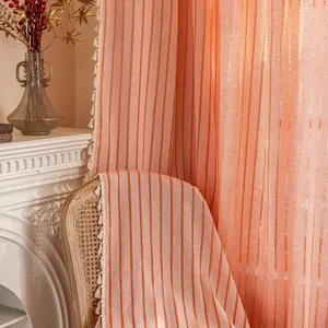 Detail of pink-orange striped cotton linen curtain with cream tassel fringe decor