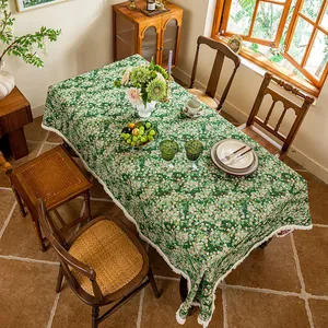 Detail of green floral tablecloth with handcrafted white tassels on a rustic table