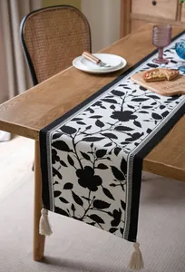 Detalle del camino de mesa jacquard blanco y negro con borlas blancas decorativas