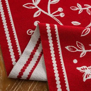 Detail of red Christmas table runner with jacquard leaf pattern and woven texture