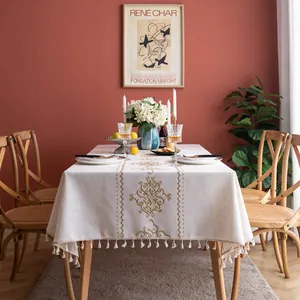 Detail of vintage cream cotton linen tablecloth with vine embroidery and tassel fringe
