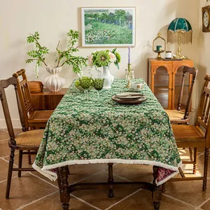 Close-up of thick floral jacquard tablecloth with white tassel edge and green patterns