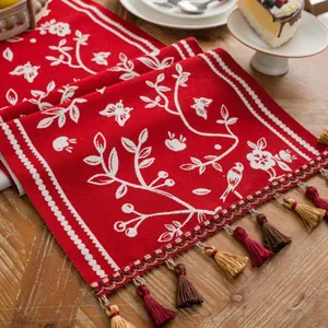 Macro detail of red knitted Christmas table runner with white floral jacquard and tassels