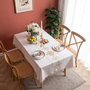 Close-up of cream tablecloth with golden baroque embroidery and fringe tassels