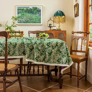 Detail of dark green floral jacquard tablecloth featuring elegant beige tassel fringe edge
