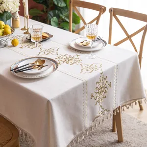 Close-up of vintage floral embroidery and tassels on beige cotton linen tablecloth