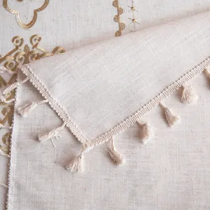 Macro shot of boho style tablecloth featuring golden embroidery and elegant edge tassels