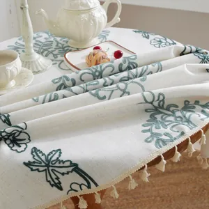 Detalle del bordado floral barroco nórdico y flecos de borlas beige en el mantel de mesa