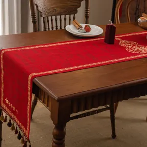 Macro detail of red festive table runner with golden embroidery and elegant tassels