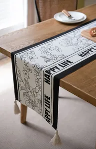 Detalle del camino de mesa jacquard nórdico con flores negras y borlas blancas
