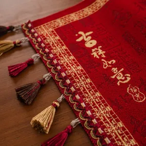 Close-up of red table runner with gold calligraphy, brocade texture and colorful tassels