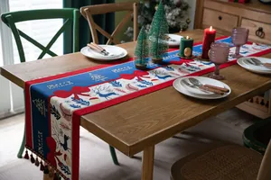 Detail of Merry Christmas table runner with reindeer motifs and colorful tassel fringe