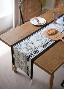 Detalle de camino de mesa jacquard floral en blanco y negro con borlas HAPPY LIFE