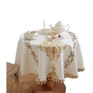 Mantel redondo crema elegante con bordado floral dorado vintage y flecos de borlas