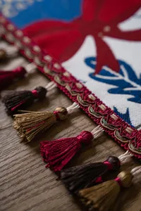 Close-up of jacquard Christmas table runner featuring red bow and multi-colored tassels