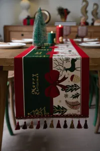 Close-up of Christmas table runner with Merry Christmas print and red ball tassels
