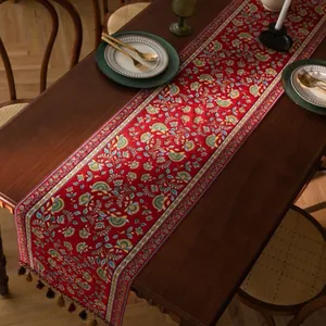 Bohemian rode tafelloper met bloemenprint en gekleurde kwastjes op een houten tafel