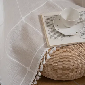Close-up of farmhouse beige plaid valance curtain with white tassels and embroidery