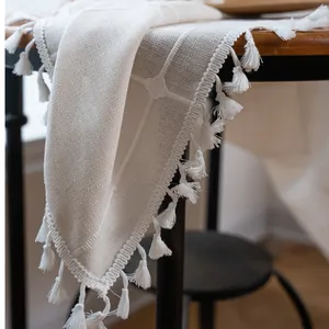 Detailed view of cream farmhouse table runner with geometric lattice and tassel trim