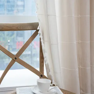 Detailed texture of beige lattice embroidery curtain with decorative fringe edge