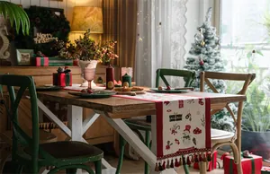Detail of a Christmas table runner with festive snowman patterns and red tassel accents