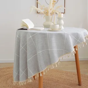 Detail of light gray linen-style tablecloth featuring large grid pattern and fringe edges