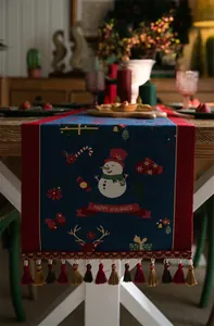 Close-up of Christmas table runner with snowman, reindeer patterns and colorful tassels