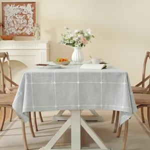 Mantel gris con aspecto de lino, diseño de cuadros con bordados y borlas decorativas