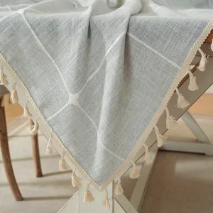 Close-up van grijs geruit tafelkleed met katoen-linnen textuur en decoratieve kwastjes