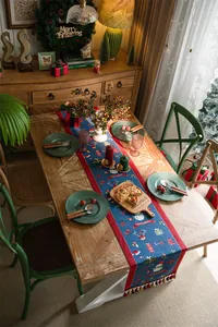 Macro detail of Christmas table runner featuring snowman reindeer patterns and tassels