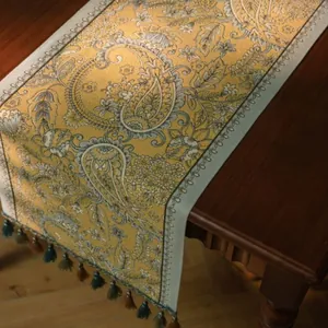 Detailweergave van de gele paisley jacquard tafelloper met decoratieve kwastjes