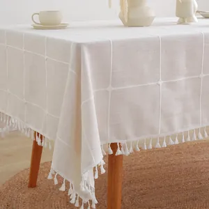 Detailopname van beige linnen tafelkleed met wit ruitjespatroon en elegante kwastjes