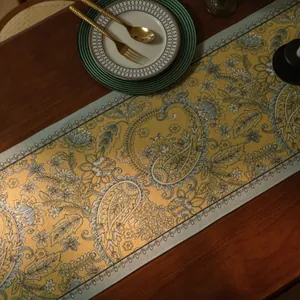 Macro detail van geel en grijs paisley tafelloper op donker hout met elegant serviesgoed