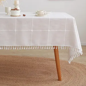 Detail van een crèmekleurig tafelkleed met ruitpatroon en franje aan de randen