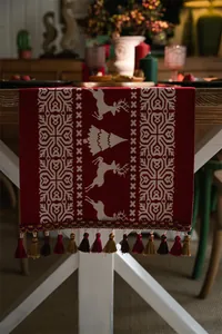 Close-up of red Christmas table runner with white reindeer jacquard and thick tassels