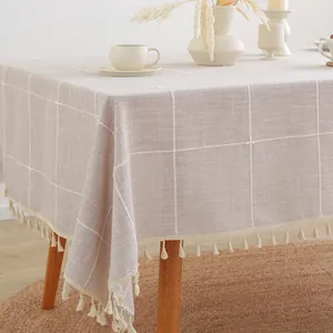 Detail van beige geruit tafelkleed met elegante kwastjes en katoen-linnen textuur