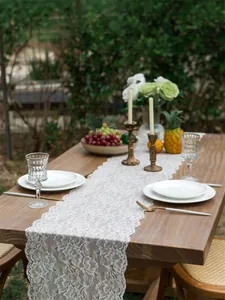 Close-up of elegant white floral lace table runner on a rustic wooden dining table