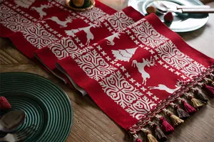 Close-up of red Christmas table runner with reindeer jacquard pattern and detailed tassels