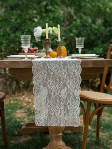 Close-up of white lace table runner with hollow floral pattern and scalloped edges