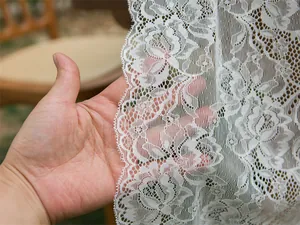 Close-up of white lace table runner showing delicate rose patterns and soft texture
