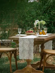 Detail of elegant white lace table runner with intricate floral pattern on dark wood table