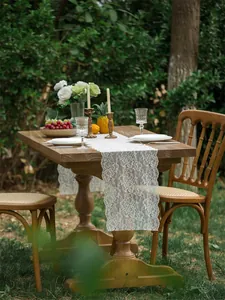Detail of white lace table runner with hollow floral pattern on a rustic wooden table