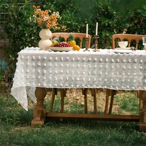 Detail einer weißen rechteckigen Tischdecke mit 3D-Pompons für elegante Hochzeiten im Freien